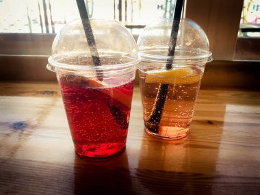 Plastik kırmızı ve sarı ferahlatıcı soğuk lezzetli tatlı ahududu çilek kiraz portakal şeftali limonlimonata doğal bir saman ve şurup kabarcıklar ile iki bardak
