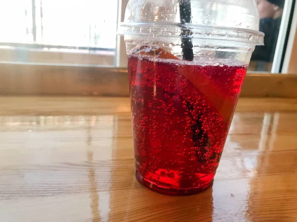 Deliciosa limonada de cereza de frambuesa dulce natural con almíbar y burbujas de gas en una taza desechable de plástico con una paja. Comida rápida, bebida — Foto de Stock