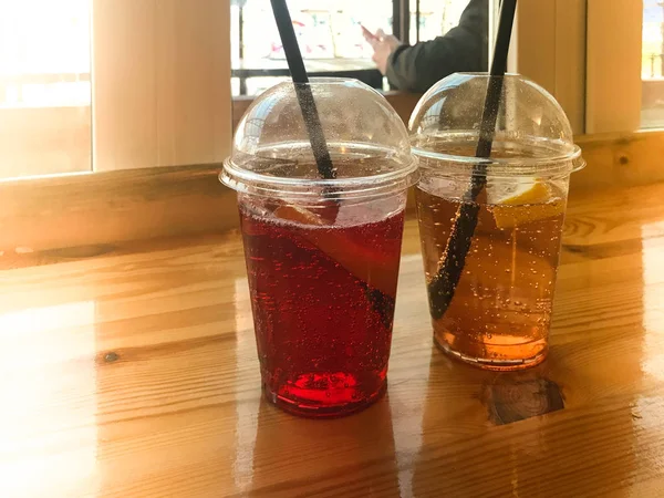 Plastik kırmızı ve sarı ferahlatıcı soğuk lezzetli tatlı ahududu çilek kiraz portakal şeftali limonlimonata doğal bir saman ve şurup kabarcıklar ile iki bardak