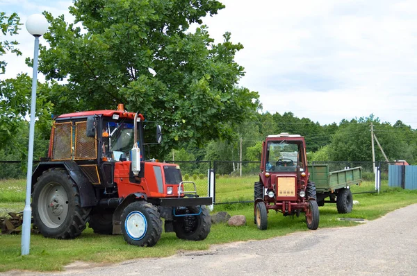 Deux tracteurs agricoles professionnels rouges avec de grandes roues avec une bande de roulement pour labourer le champ, la terre, le transport de marchandises — Photo