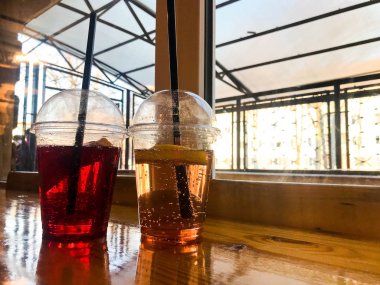 Plastik kırmızı ve sarı ferahlatıcı soğuk lezzetli tatlı ahududu çilek kiraz portakal şeftali limonlimonata doğal bir saman ve şurup kabarcıklar ile iki bardak