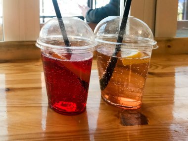 Plastik kırmızı ve sarı ferahlatıcı soğuk lezzetli tatlı ahududu çilek kiraz portakal şeftali limonlimonata doğal bir saman ve şurup kabarcıklar ile iki bardak