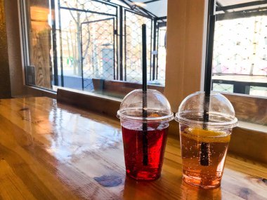 Plastik kırmızı ve sarı ferahlatıcı soğuk lezzetli tatlı ahududu çilek kiraz portakal şeftali limonlimonata doğal bir saman ve şurup kabarcıklar ile iki bardak