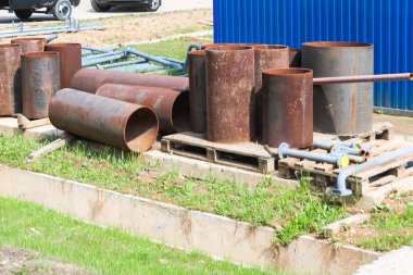 Büyük endüstriyel paslı demir borular üzerinde duruyor.