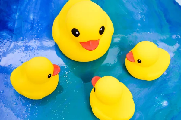 一群黄色的橡胶鸭正站在环氧树脂水蓝色和白色表面上的一个圆圈上。和孩子们一起游泳用的生态橡胶鸭 — 图库照片