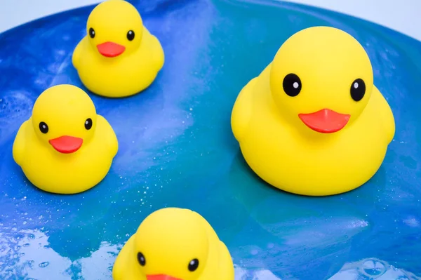 Patos de goma amarilla flotando en la superficie del océano de epoxi. juguetes decorativos de pie en una imagen interior brillante en forma de agua con resplandor solar. fondo abstracto —  Fotos de Stock