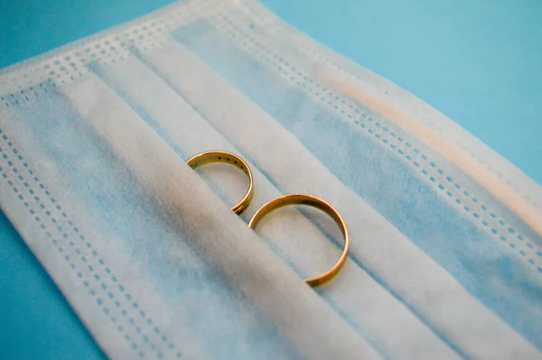 wedding rings lie on a white cotton mask at a wedding. Covid family creation ceremony. masked husband and wife on holiday. rings on a disposable mask on a blue background