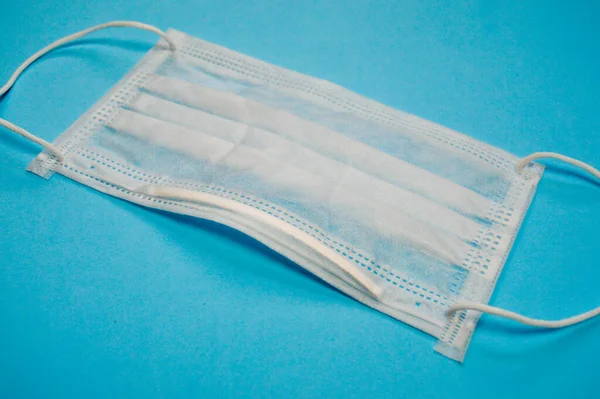 Mavi tıbbi steril arka planda tek kullanımlık beyaz maske. Kişisel solunum koruması. Viral solunum hastalıklarının önlenmesi — Stok fotoğraf