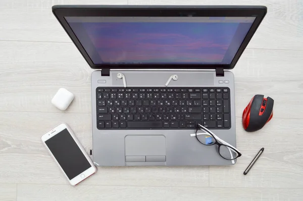 Local de trabalho em casa, escritório em casa para trabalho remoto com computador laptop celular smartphone notepad caneta fones de ouvido e óculos em um fundo de madeira — Fotografia de Stock