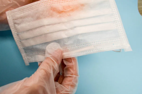 a man in disposable protective gloves prepare to put on an individual cotton mask to protect respiratory respiratory organs. disposable mask on a blue background