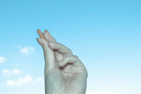 Main féminine avec manucure tient une tablette ovale contre le ciel. main noire et blanche avec médicament. Photo artistique de la prise de pilules, de substances médicales. contexte de la drogue — Photo