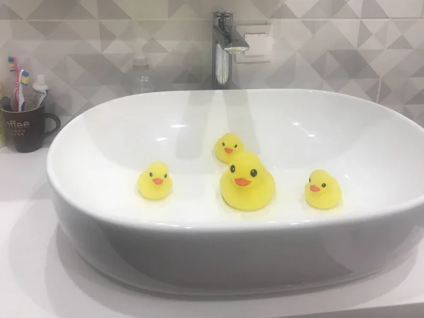 由于海洋和水污染，黄鸭一家在水槽里游泳。环境污染和缺乏自然资源。橡胶玩具鸭在浴缸里洗澡 — 图库照片