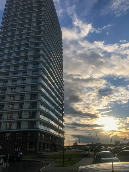 Високий житловий блок квартир, колона в центрі міста. будинок нового формату, білий, без балкона зі скляною терасою і багатьма вікнами. на фоні яскравого сонячного неба — стокове фото