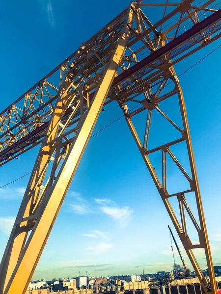 Grúa pórtico para la construcción de un metro en el centro de la ciudad, amarillo, contra el cielo. grúa tipo puente, cuyo puente está instalado sobre soportes que se mueven a lo largo de rieles instalados sobre cimientos —  Fotos de Stock