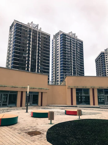 There is a round beige shopping center in the residential yard. bright round benches stand for shoppers. behind are the blue glass tenements for the tenants. urban landscape — Stock Photo, Image