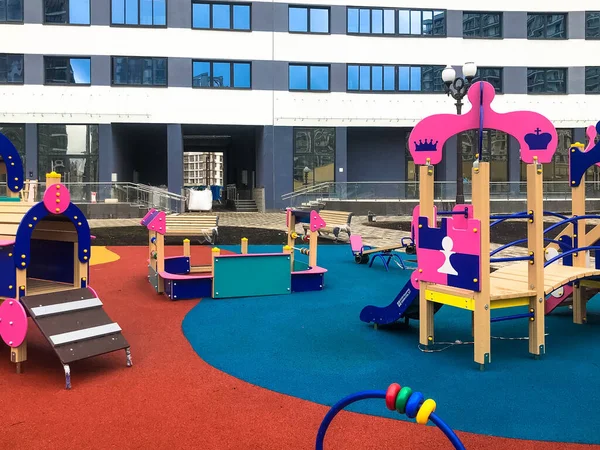 Children's pink playground in the center of the residential complex. for kids there are swings, abacus, fun slides and climbing frames. playground in a new area next to tall apartment buildings — Stock Photo, Image