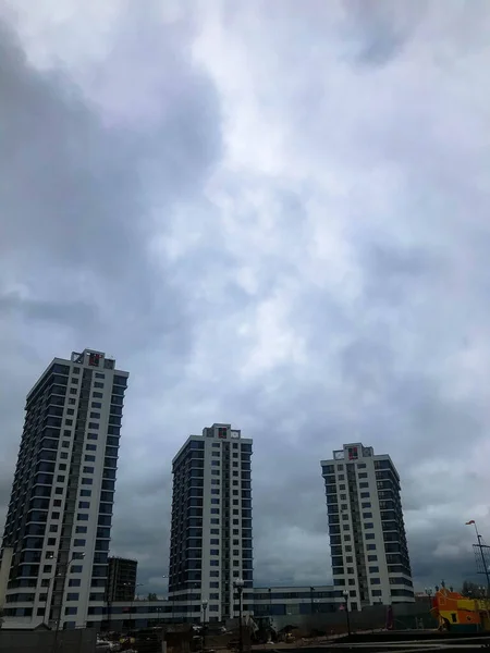 Stock image three new, unusual and tall apartment buildings in the city. against the backdrop of a cloudy rainy blue sky. next to a playground with different entertainment. bright new courtyard