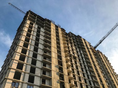 Yeni bir yerleşim alanı inşaatı. Beton gri bloklardan evler inşa ediliyor. Evin henüz ne kapısı ne de penceresi var. Cam ve balkon için delikler oluşturuldu. Turnalar taşır