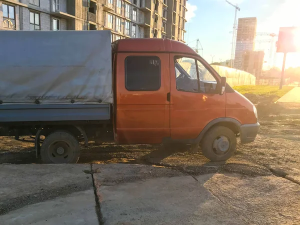 A truck with an orange cab and a gray base stands on the ground. a car with small wheels for transporting goods. transport for building materials, sand and goods — Stock Photo, Image