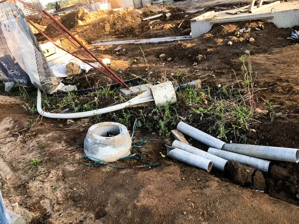 Hay estructuras de hormigón, piezas de repuesto, tuberías, círculos de metal en el sitio de construcción. colocación de comunicaciones subterráneas. creación de drenajes de agua para prevenir la contaminación de las aguas subterráneas — Foto de Stock