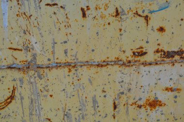 Paslı, sarı ve çukurlu. Paslanmış, paslanmış bir metal parçası, yağışla yok olmuş bir boya. Metallerin birleştiği yerde pasla kaplanmış bir dikiş izi oluştu.