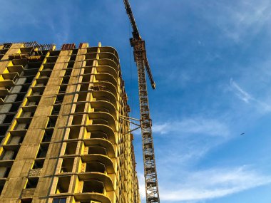 Yeni bir bina inşa etmek. Bir vinç zemini inşa etmek için ağır beton levhalar taşır. Penceresiz evler, alışılmadık kıvrımlar. Sakinlerin rahatlığı için yeni teknoloji