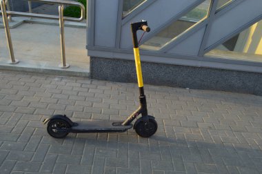 İnsanların binmesi için küçük tekerlekli parlak sarı elektrikli scooter. Yerdeki yaya nakliyesinin kirası. Hareket kolaylığı. Şehirdeki yeşil erişilebilir çevre, çevreye özen