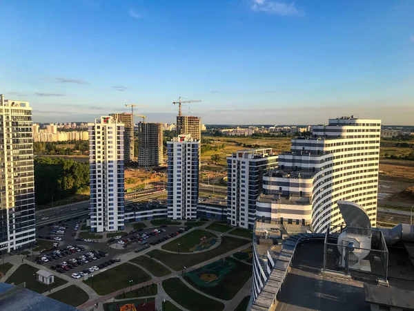 Höga hus är i ett nytt område i en halvcirkel. ett av husen med en ovanlig vågig form. blå och vita glashus. det finns ett köpcentrum i centrum — Stockfoto