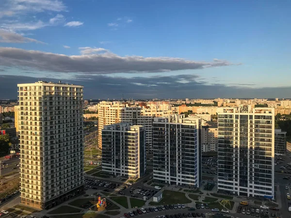 Altas casas de cristal azul y blanco se alinean en altura. las casas se hacen en el mismo estilo. nuevo microdistrito, casas con ventanas panorámicas. contra el fondo de nubes oscuras —  Fotos de Stock