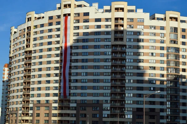 Beyaz-kırmızı-beyaz büyük ve uzun bayrak evin üzerinde sıradışı bir şekilde asılı duruyor. Kahverengi ve bej tuğlalardan yapılmış taç şeklinde yeni bir bina. Muhalif bayrak cepheye asıldı.