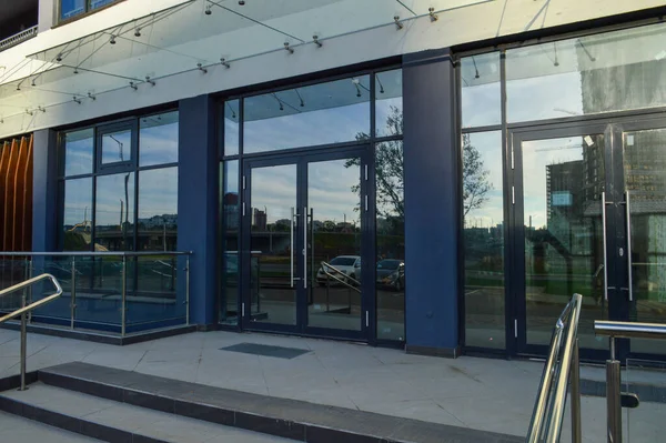 entrance group to the house. glass doors with large panoramic windows to the new building. blue color of the facade, made of glass. upstairs rain canopy, opposite the railing