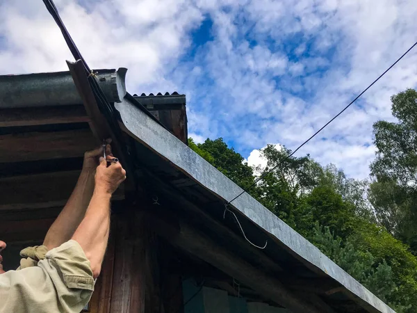 Man repairs the roof at a height. manufacturing in a wooden house. sealing holes, holes in a residential building. roof fitter. manufacture of wooden roof covering — Stock Image Man repairs the roof at a height. manufacturing in a wooden house. sealing holes, holes in a residential building. roof fitter. manufacture of wooden roof covering Royalty Free Stock Images