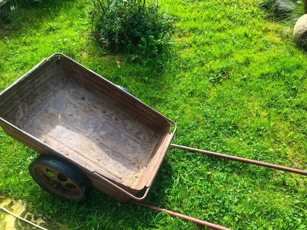 Brouette métallique pour l'entretien du jardin. rose, vieux chariot rouillé pour le transport d'engrais, pommes de terre, fruits du verger. poignée longue pour rouler le chariot. jardinage — Photo