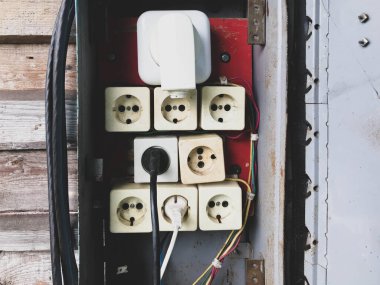 Düğme kutusu. Elektrik kabloları için ev yapımı bir kalkan. Bağlantı kablosu. Bir sürü beyaz gül, en büyük beyaz. Yüksek voltajlı bir elektrik hattı oluşturuluyor.