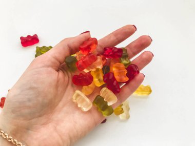 gummy multicolored bears lie on a hand with a gold bracelet. colored bears made from gelatin, high-calorie dessert. treats for children and adults. tasty candy