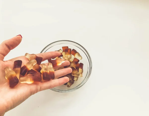 A geleia na forma de uma garrafa vaza-se da mão em uma chapa redonda. sobremesa para crianças e adultos. deliciosas gomas suculentas. doces gelatinosos de frutas — Fotografia de Stock