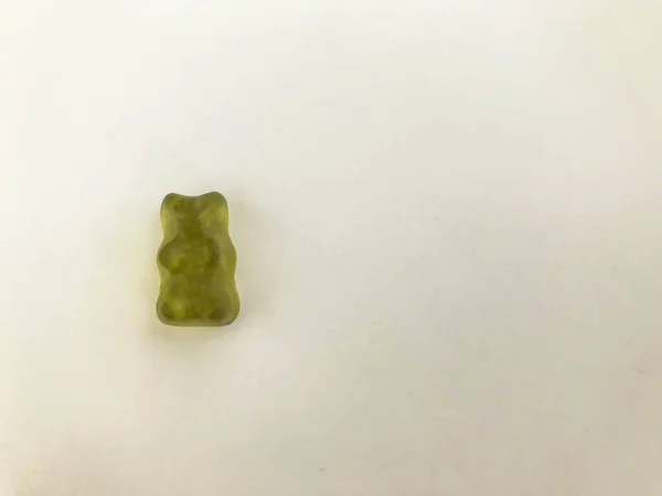 Urso gelatinoso verde sobre um fundo laranja fosco. figura de goma na forma de um animal. Doces. Urso de peluche, gammi. estatueta apetitosa para comer — Fotografia de Stock