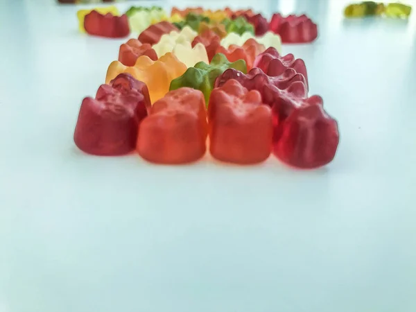 voluminous, bright gelatinous gummy bears. bears lie on a matte background. bears are stacked in one row in the shape of a figure. decorating cakes and desserts