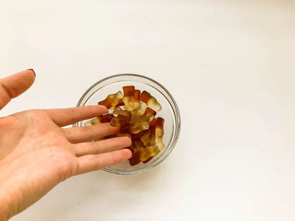 Doces gelatinosos de frutas. a geleia na forma de uma garrafa vaza-se da mão em uma chapa redonda. sobremesa para crianças e adultos. deleite saboroso e doce — Fotografia de Stock