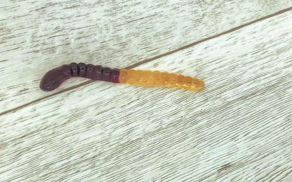 Gummiwurm liegt auf einem Holzlaminat. Süßigkeiten liegen auf dem Boden. Wohnkultur zu Halloween. Beängstigende Atmosphäre für den Urlaub — Stockfoto