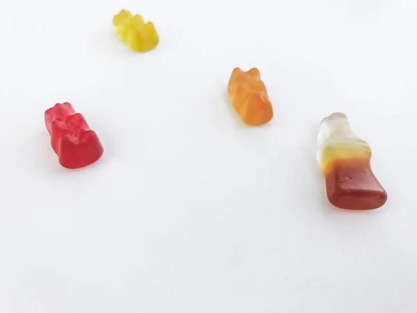 Gummy αρκούδες σε λευκό ματ φόντο. κόκκινη, κίτρινη και πορτοκαλί αρκούδα βρίσκονται στο τραπέζι. δίπλα τους μαρμελάδα με τη μορφή ενός μπουκαλιού λεμονάδα. γλυκά για τη διακόσμηση κέικ και αρτοσκευασμάτων — Φωτογραφία Αρχείου