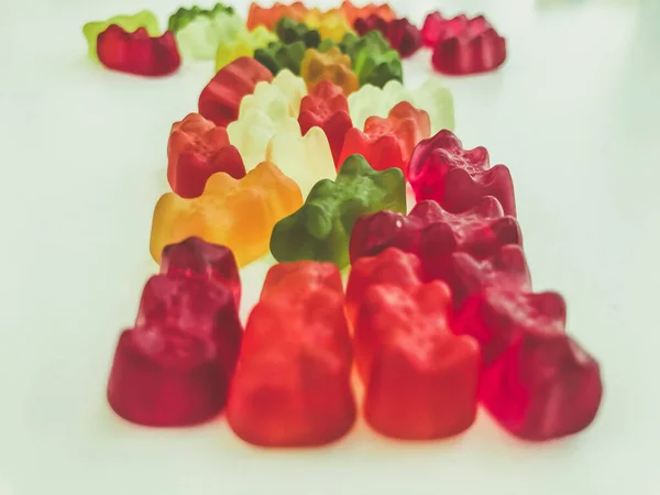 voluminous, bright gelatinous gummy bears. bears lie on a matte background. one row of bears. volumetric figure. bears are laid out in three rows. sweets for decorating cakes and pastries
