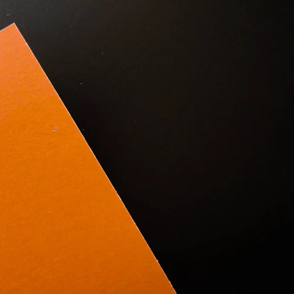 Dark flat lay background with color paper sheets. Black and orange.