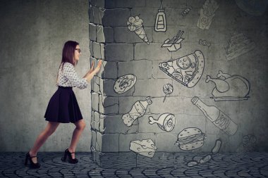 Hızlı ayak yeme ve daha iyi beslenme seçme temptation direnerek motive bir genç kadın yan görünüm. 
