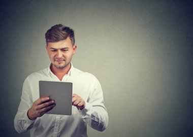 Casual adam beyaz gömlekli modern tablet gri yeni aygıt ayakta zevk tarama içerik. 
