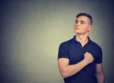 Casual adam uzakta gri arka plan üzerinde olmak gurur ve seyir göğsünde elini tutarak tespit