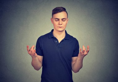 Gri arka plan üzerinde gözlerini tutmak meditasyonda elele konsantre genç adam kapalı 