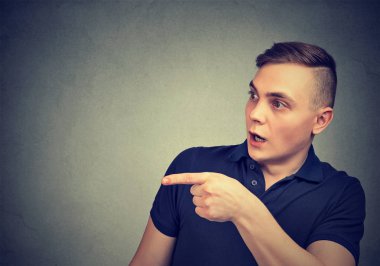 Genç adam uzakta güvensizlik ayakta gri arka plan üzerinde işaret hayret