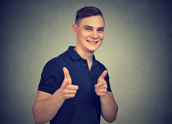 Content positive man pointing at camera with fingers looking cool and giving like on gray background