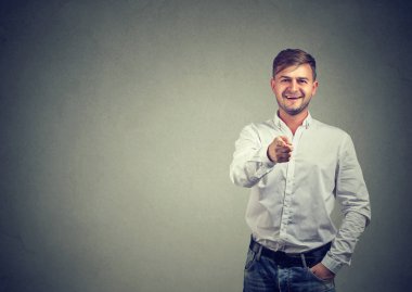 Gülümseyen ve gri arka plan üzerine kararı kamera işaret neşeli casual adam
